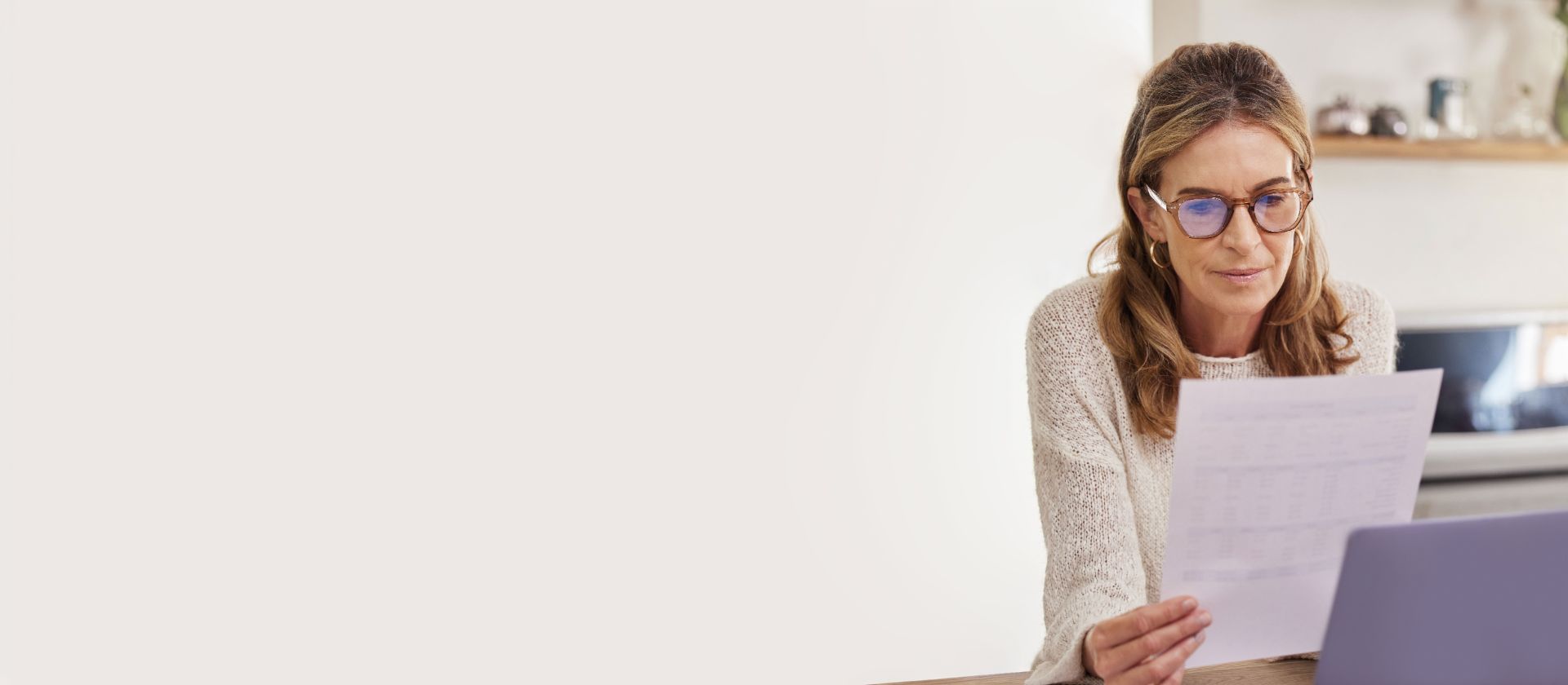 Femme portant des lunettes examinant une lettre EOS à son bureau – réglez vos créances impayées facilement