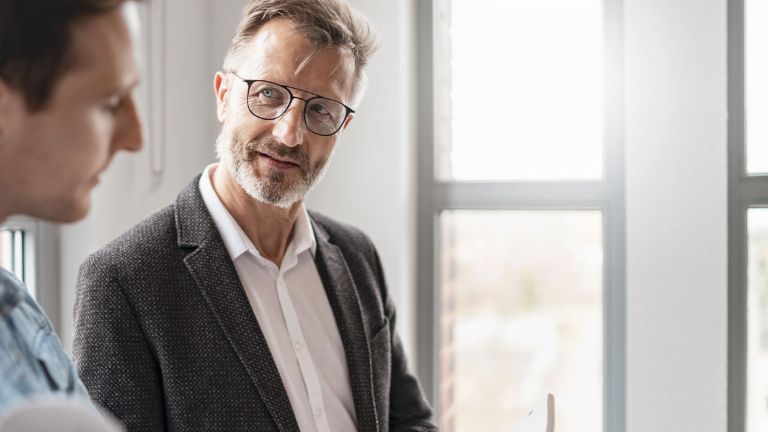 Deux hommes dans un bureau discutent des résultats de l'étude « Pratiques de Paiement Européennes 2025 » du groupe EOS sur la numérisation dans la gestion des créances.