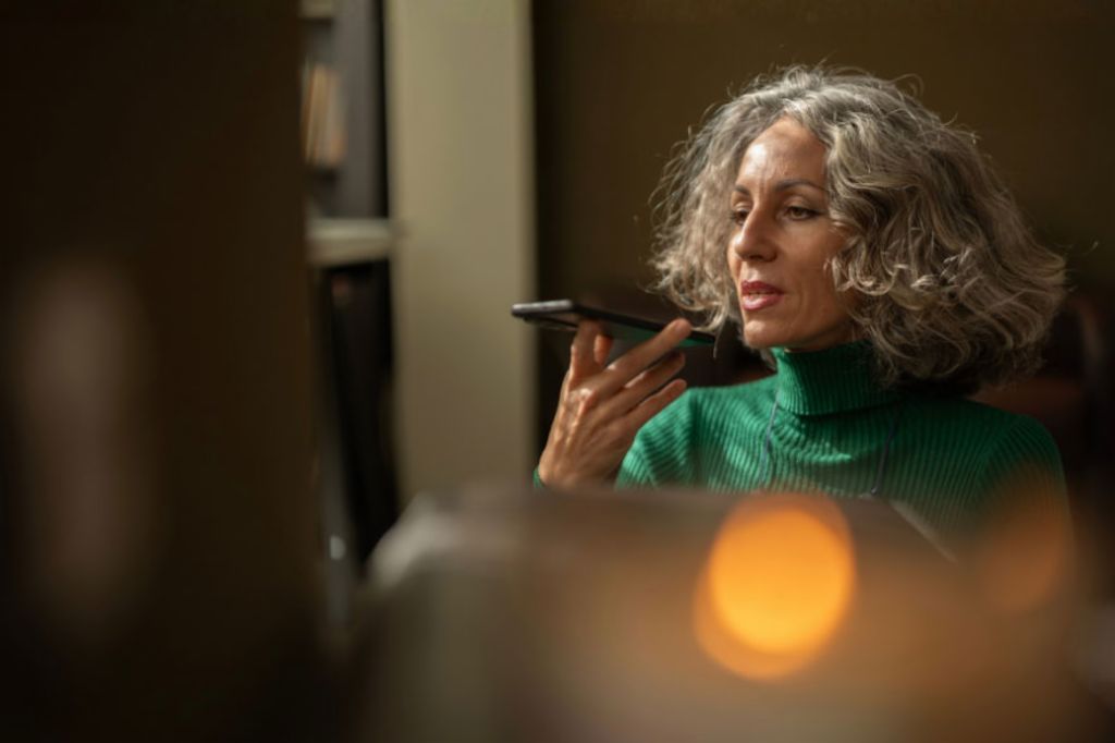 Une femme tenant un téléphone portable parle à l’intelligence artificielle.