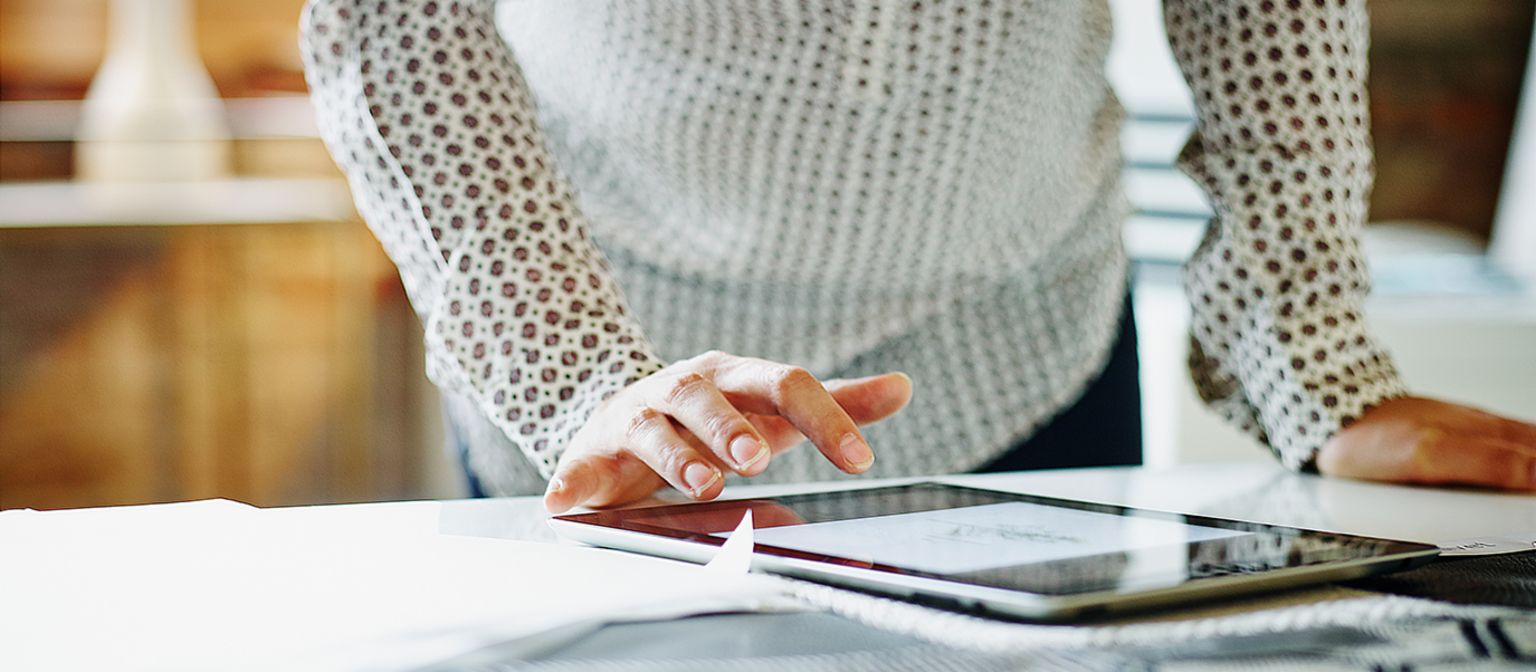 Women at desk, typing on a tablet