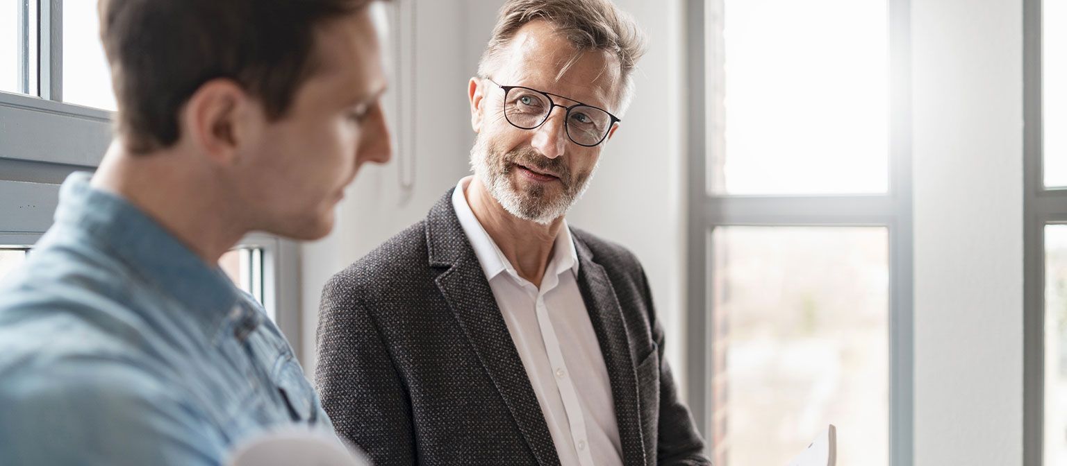 Deux hommes dans un bureau discutent des résultats de l'étude « Pratiques de Paiement Européennes 2025 » du groupe EOS sur la numérisation dans la gestion des créances.