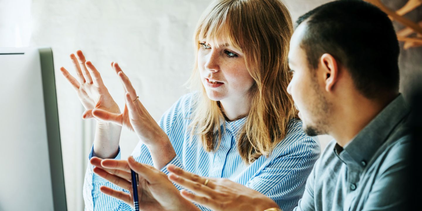 Agile working: A couple of co-workers discuss something in front of a monitor.