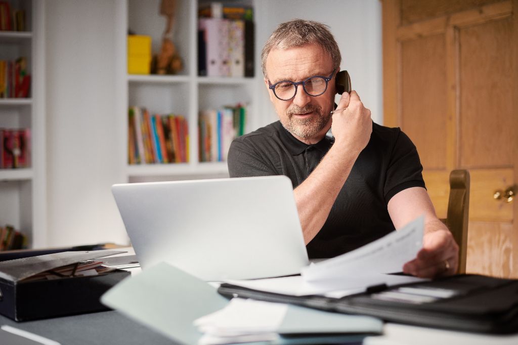 Midaged man talking on the phone to clarify his debt collection