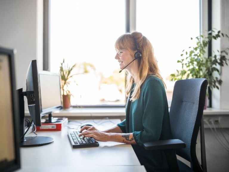 Eine junge Frau mit Headset arbeitet am Computer