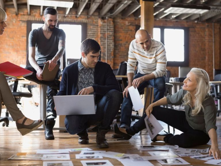 Agile working: A group of employees discuss pieces of paper on the floor.