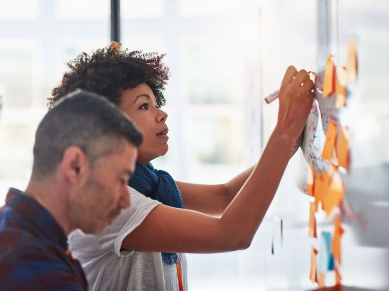 Agile working: A couple of co-workers in front of a wall with post-its.