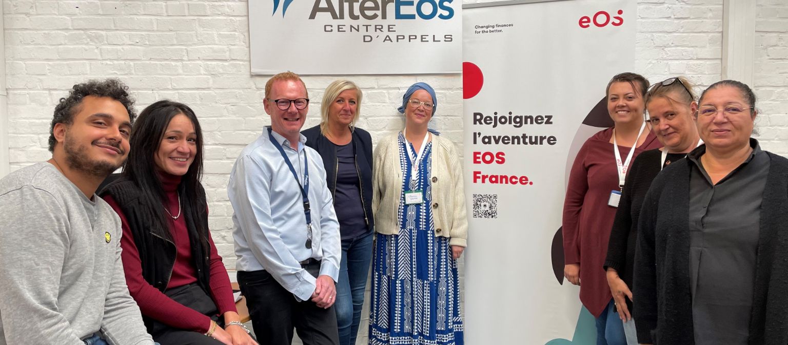 A group of eight people standing in front of an EOS banner and an AlterEOS banner facing the camera.